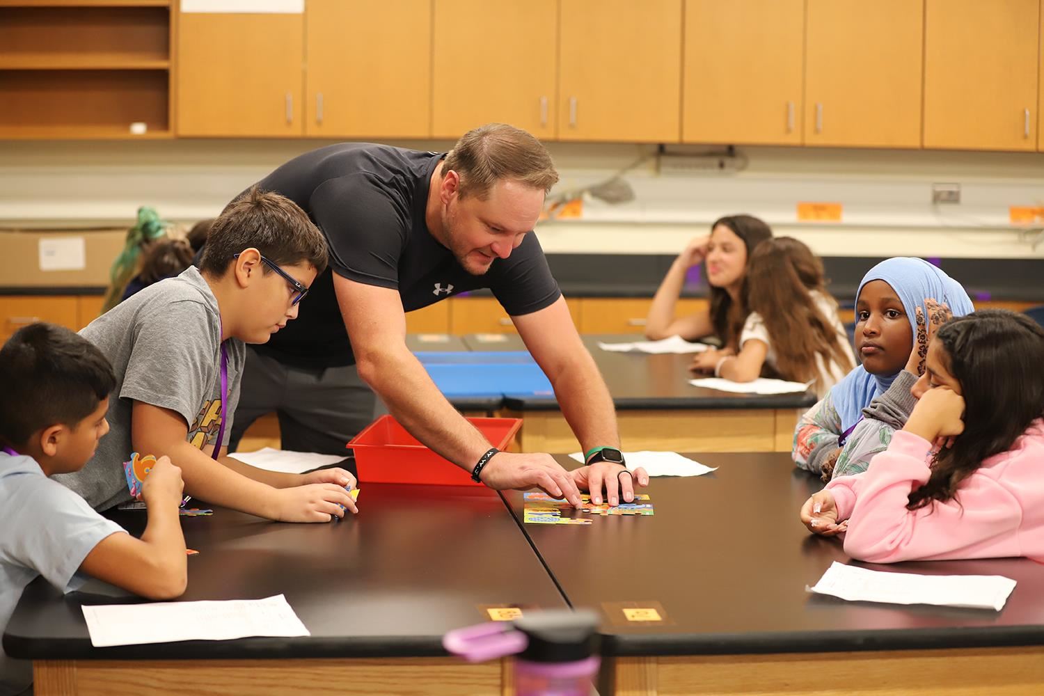 Barr Middle School Science Teacher working with 6th Grade students on a puzzle project.